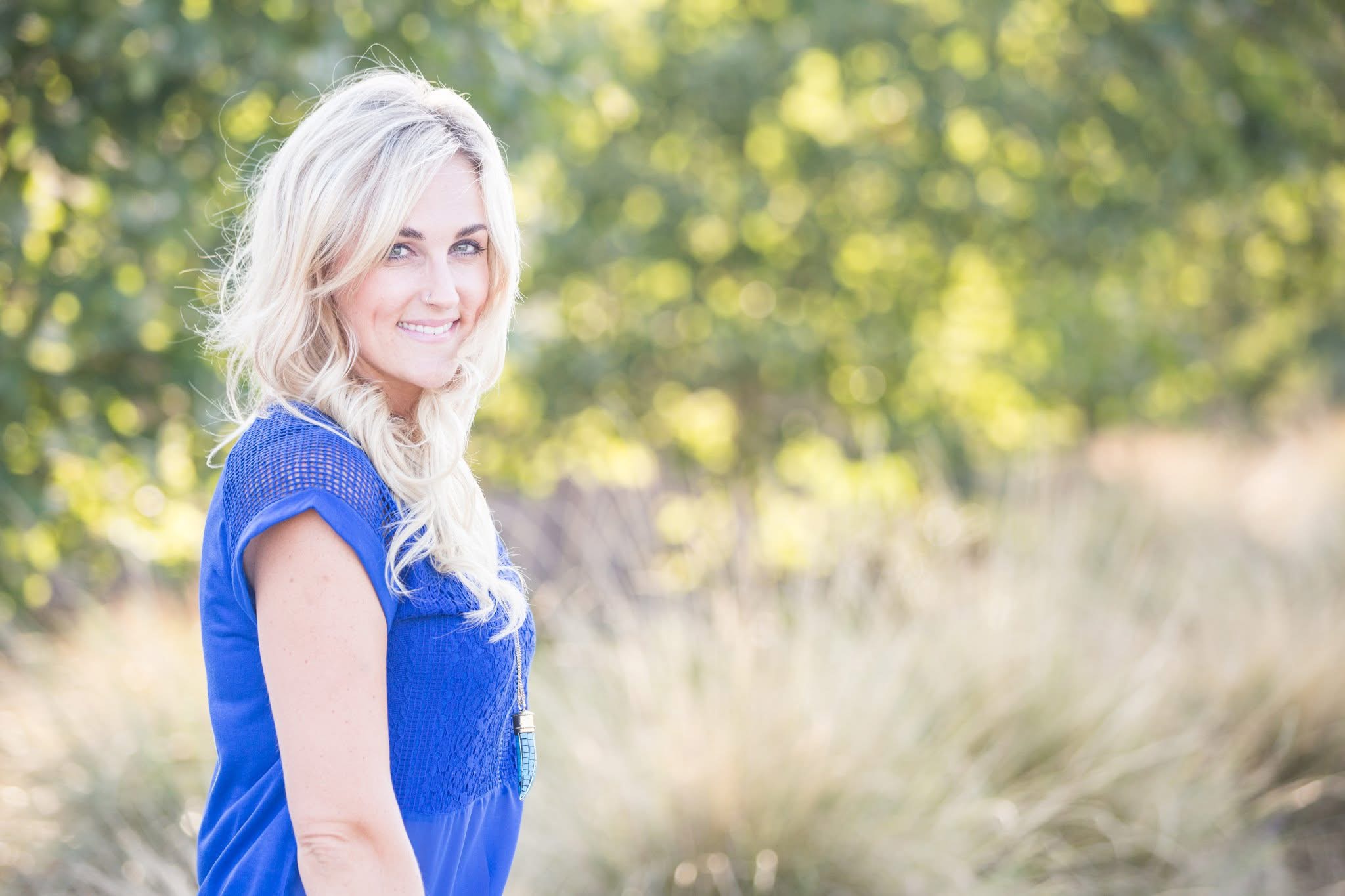 Shannon smiling outdoors in a blue dress